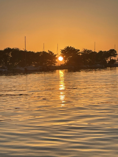 Coucher soleil sur lac avec arbres et bateaux en fond